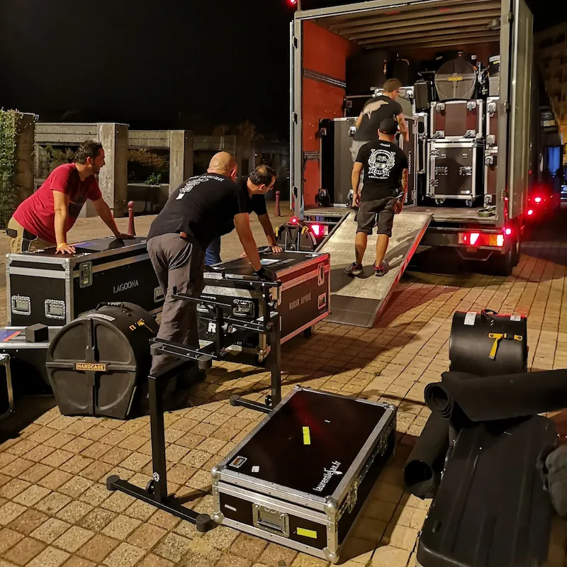 Mehrere Personen verladen nachts Flightcases und Musikequipment in einen LKW – Referenzbild eines Kunden.