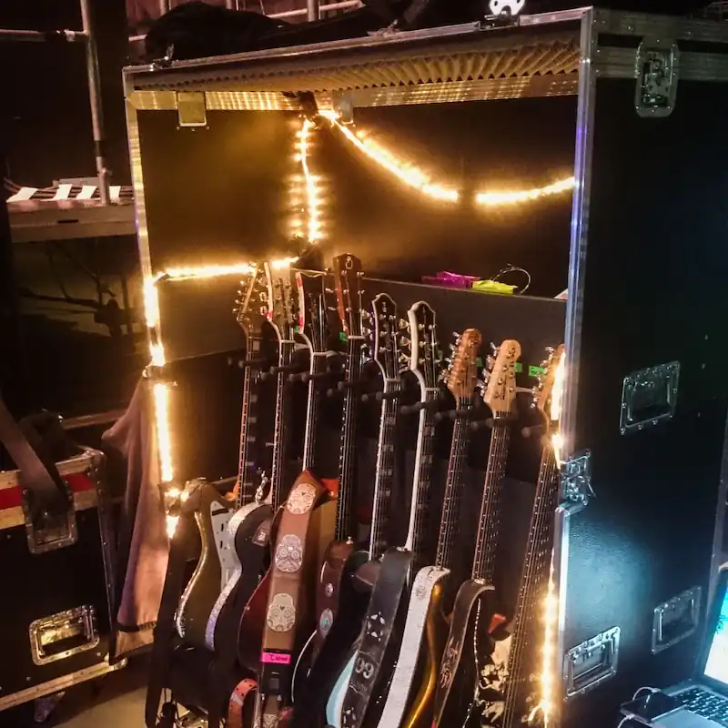 Ein beleuchtetes Gitarrenrack-Case mit mehreren E-Gitarren auf einer Bühne – Referenzbild eines Kunden.